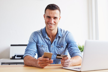 Man sitting in office and pays by credit card