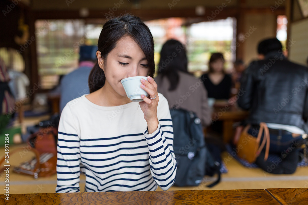 Poster Woman drink of tea in Japanese restaurant