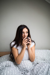 Beautiful woman drinking a coffee in her bed