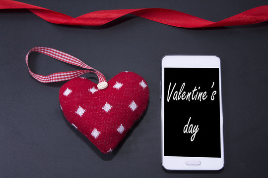 Heart-shaped tag and mobile phone on blackboard background