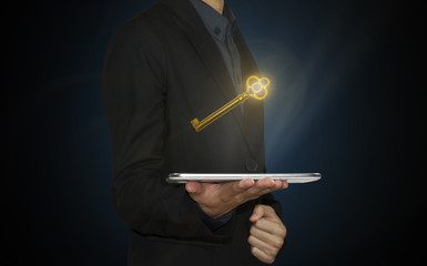 businessman hand holding tablet with gold key. concept unlock business success.