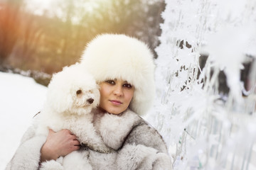Beautiful woman in the winter time with her dog. Woman wearing a winter coat. Lens flare in the background.