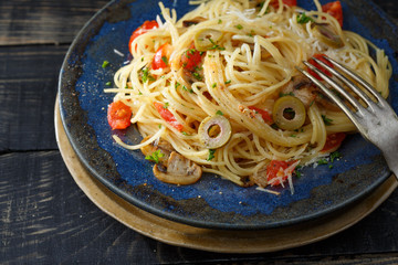 vermicelli pasta and tomatoes seasoned with , olives, herbs, mushrooms and Parmesan cheese on an old plate