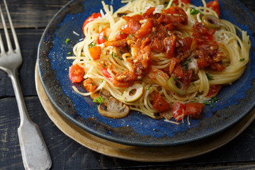 vermicelli pasta and tomatoes seasoned with , olives, herbs, mushrooms and Parmesan cheese on an old plate