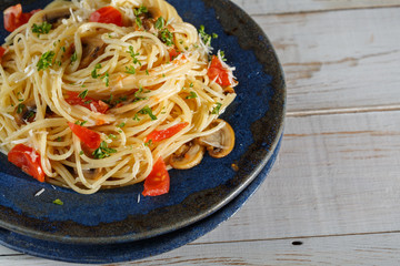 vermicelli pasta and tomatoes seasoned with , olives, herbs, mushrooms and Parmesan cheese on an old plate