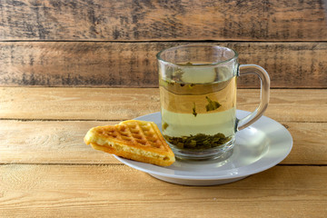 Green tea in a transparent mug with waffle