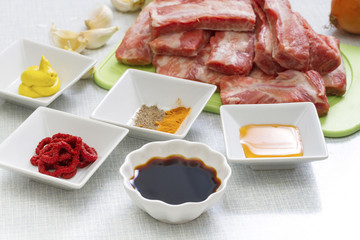 Raw pork ribs on a cutting board and  set of spices for cooking.