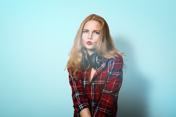 Blonde girl in a checkered shirt with headphones. beautiful girl in a plaid shirt is listening to music. Artistic portrait.