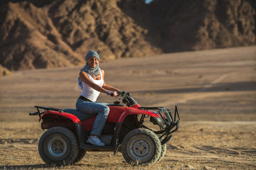 The woman ride a quad bike in the desert