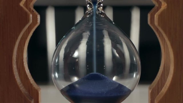 Hourglass with blue sand. Close-up.