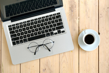 Laptop, glasses and coffee cup on wooden desk, top view