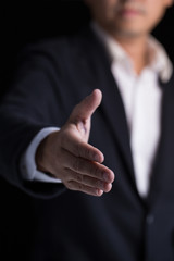 A business man wearing black suit giving one hand for shaking in cooperate look.