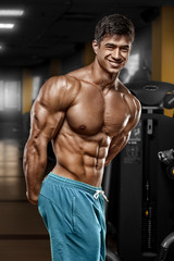 Sexy muscular man in gym, shaped abdominal. Strong male naked torso abs, working out