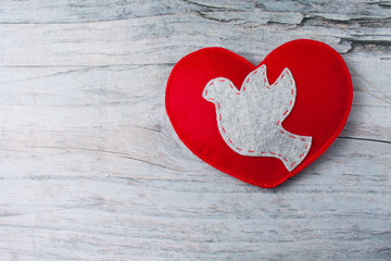 Felt grey dove, red hand made heart on wooden background