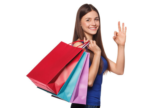 Smile beautiful happy woman holding shopping bags and showing okay sign, isolated on white background