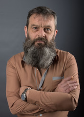 Photo of an angry grumpy old man looking very displeased. Male man with long beard on his face. Close up face looking into the camera.