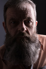 Photo of an angry grumpy old man looking very displeased. Male man with long beard on his face....