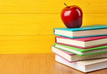 Books and apple on wooden background