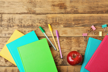 Books, apple and accessories on wooden background