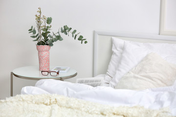 Bedroom interior with bed and flowers on nightstand