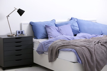 Bedroom interior with bed and nightstand on light wall background