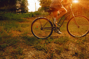 Fototapeta premium Vintage image of young hipster female on city bike fixie at the park. Summertime. Freedom teenager with her happy vacation travel retro look