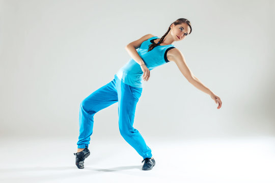 Young beautiful slim girl in blue dancing on a white studio background