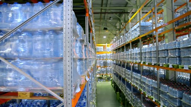 Camera cranes up on shelves of pure bottled water inside a storage warehouse.