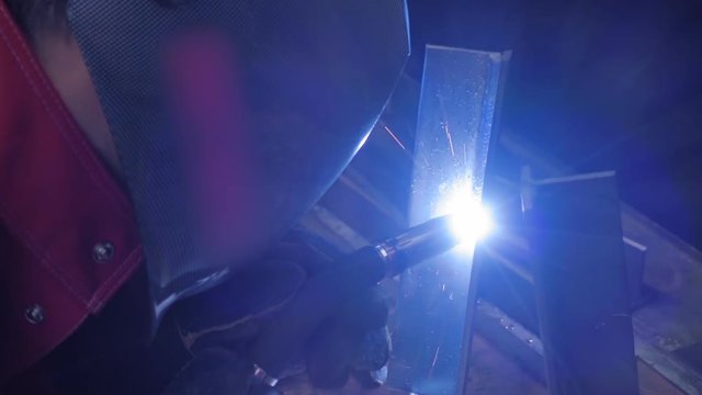 Welder is going welding of the metal profile. Sparks are flying in different directions. Slow motion, high speed camera, 250fps
