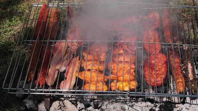 Carnes variadas asandose a la parrilla, con las brasas y la ceniza echando humo