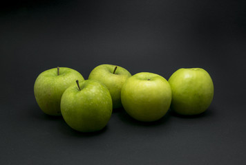 Green apples on black background.