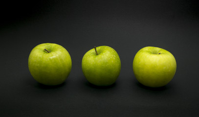 Green apples on black background.