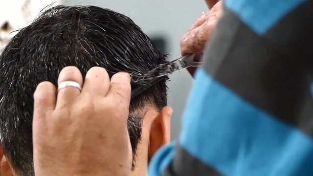 The man is standing and making haircut for a man.