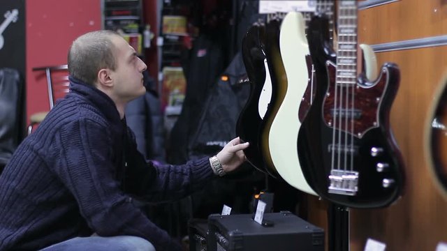Shop musical instruments. Man chooses an electric guitar