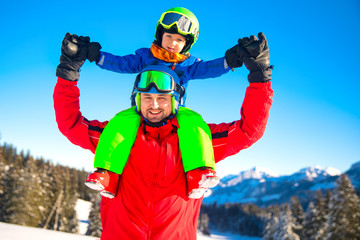 Little boy having fun with his caucasian attractive father during skiing in Alps