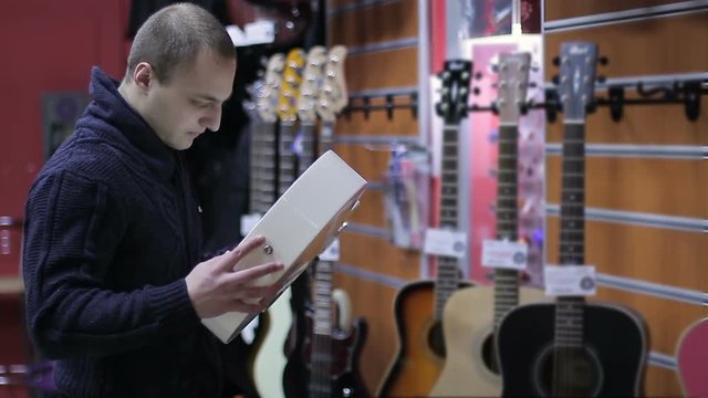 Shop musical instruments. Young Man chooses a guitar