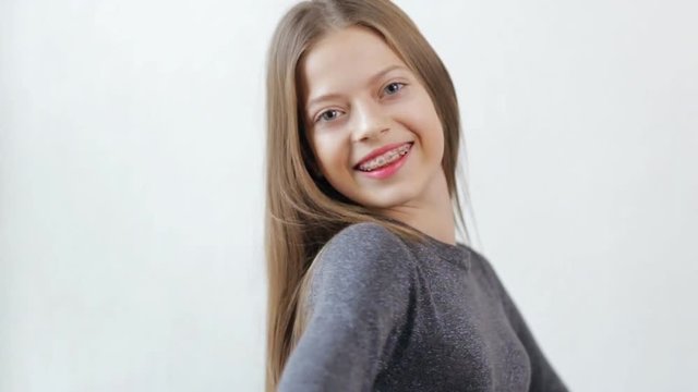 Teen girl in braces smiling to camera, white background