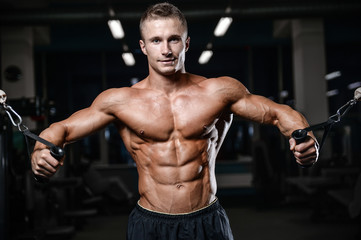 Naklejka na ściany i meble Handsome fitness model train in the gym gain muscle
