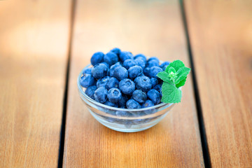 Blueberries in glass bowl on wooden deck