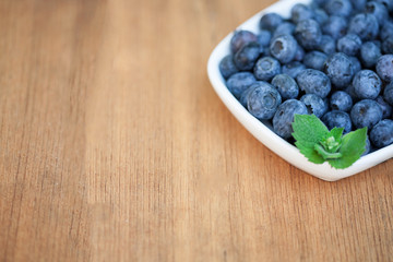 Blueberries on white plate on wooden deck