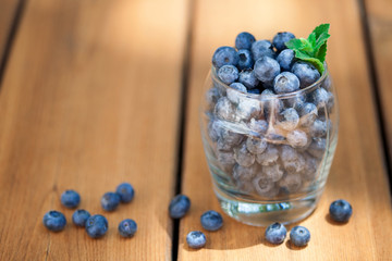 Blueberries in glass on wooden deck space background for text