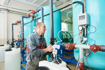 Obraz premium serviceman operating industrial water purification or filtration equipment