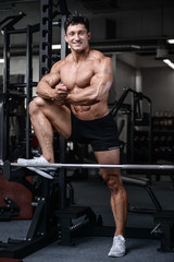 Fototapeta na wymiar Handsome bodybuilder training in the gym sexy man lift dumbbells
