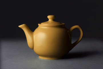 Matte orange ceramic teapot isolated on black background