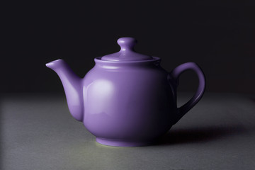 Matte violet ceramic teapot isolated on black background