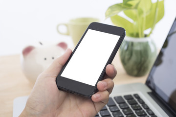 Business hand holding smart phone with white screen isolated on desk office background.