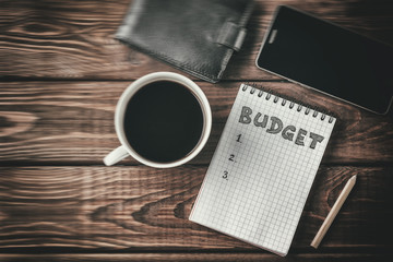 Budget planing concept. Top view of notepad with word Budget, mobile phone, cup 