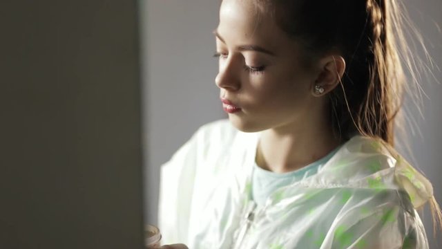 Teen girl in windcheater making makeup before mirror