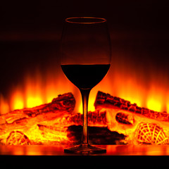 Glass of wine next to the fireplace.