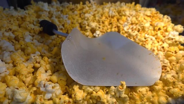 Heap of flakes in the machine for the preparation of popcorn and a scoop for distributing of portions. Shot in motion